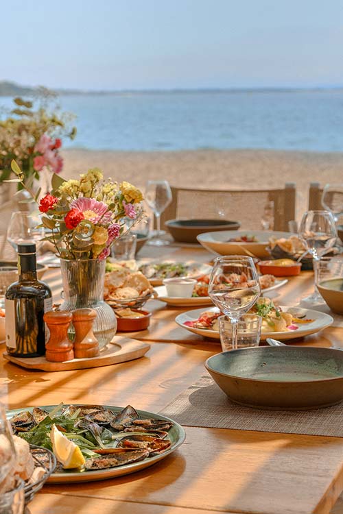 Table dressée sur la terrasse du restaurant L'Aventure, vue sur la mer et les rochers de la plage Péno à Carqueiranne