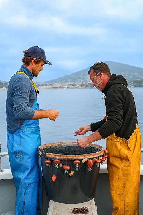 Deux pêcheurs préparant leurs lignes sur leur bateau dans la baie de Carqueiranne — poissons frais livrés chaque matin au restaurant L'Aventure pour la bouillabaisse