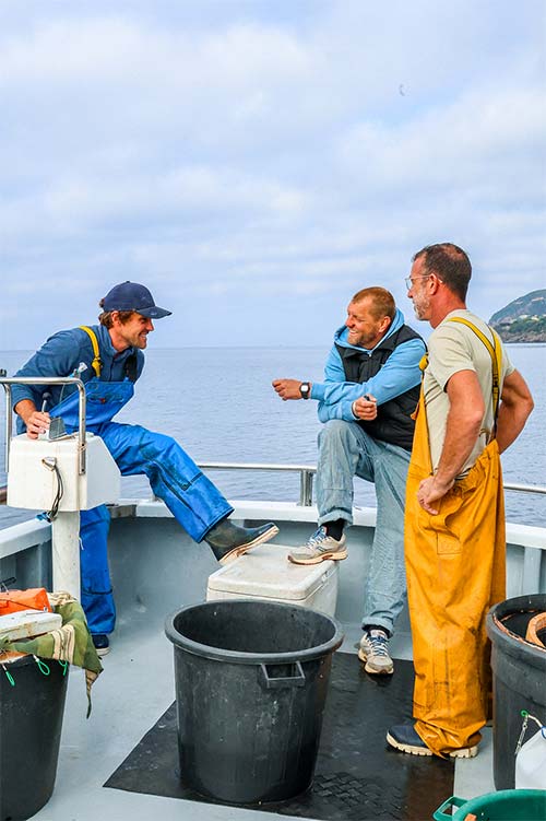 Julien le patron de L'Aventure avec Jordan et Tof sur le bateau de pêche dans la baie de Carqueiranne — une relation de confiance au cœur du restaurant