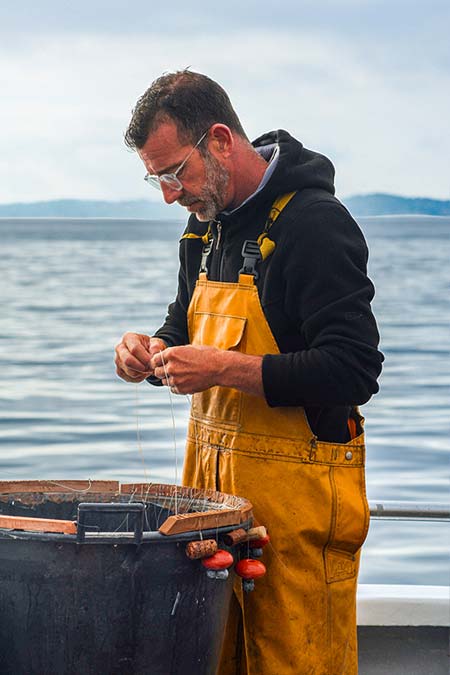 Pêcheur tenant un poisson frais pêché à la ligne à Carqueiranne, arrivage quotidien au restaurant L'Aventure